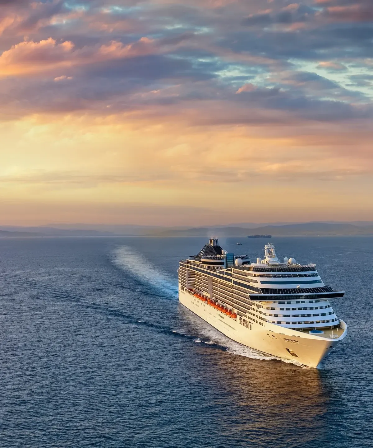 A cruise ship sailing on open ocean at sunset